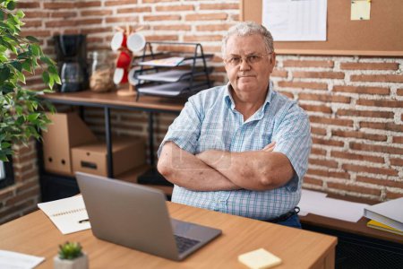 Téléchargez les photos : Homme d'âge moyen aux cheveux gris homme d'affaires souriant confiant assis avec les bras croisés geste au bureau - en image libre de droit