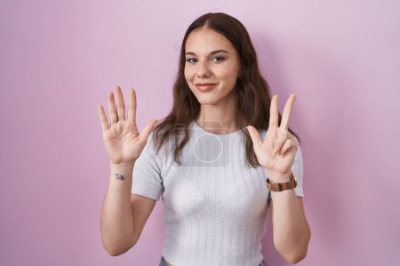 Photo for Young hispanic girl standing over pink background showing and pointing up with fingers number eight while smiling confident and happy. - Royalty Free Image