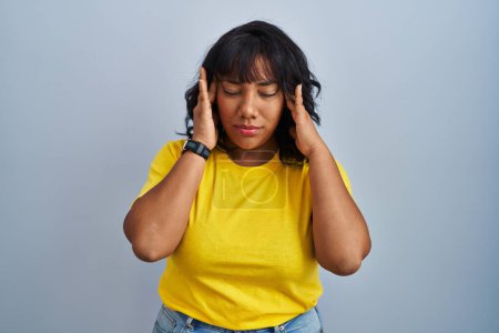 Foto de Mujer hispana de pie sobre fondo azul con la mano en la cabeza, dolor de cabeza porque el estrés. padecer migraña. - Imagen libre de derechos