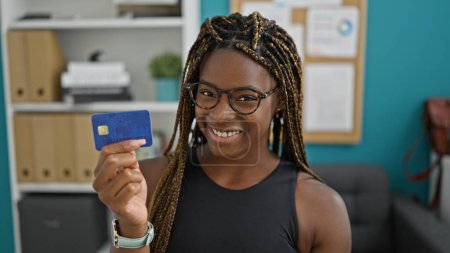 Photo for African american woman business worker holding credit card smiling at the office - Royalty Free Image