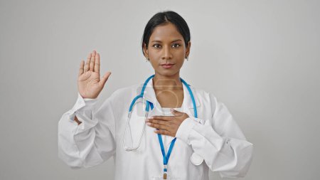 Téléchargez les photos : Femme afro-américaine médecin faire un serment avec la main sur la poitrine sur fond blanc isolé - en image libre de droit