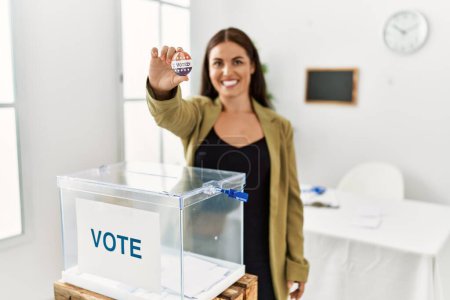 Foto de Joven mujer hispana hermosa mesa electoral presidente con insignia de voto en colegio electoral - Imagen libre de derechos