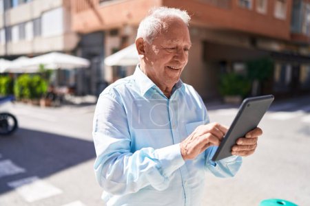 Photo for Middle age grey-haired man smiling confident using touchpad at street - Royalty Free Image