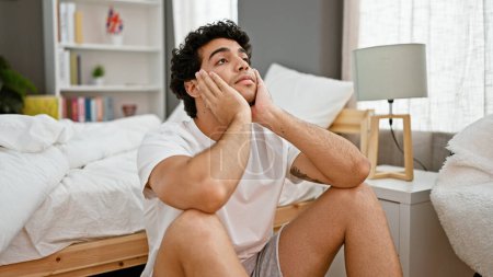 Photo for Young latin man stressed sitting on floor at bedroom - Royalty Free Image