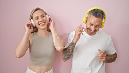 Foto de Hombre y mujer pareja escuchando música bailando sobre un fondo rosa aislado - Imagen libre de derechos