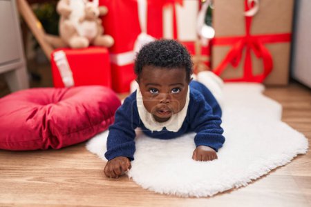 Téléchargez les photos : Bébé afro-américain couché sur le sol par des cadeaux de Noël à la maison - en image libre de droit