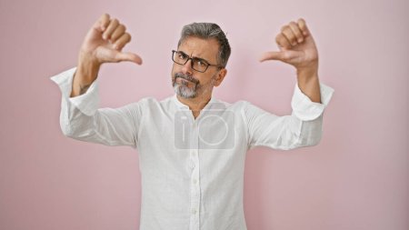 Photo for Young hispanic grey-haired man standing with serious expression doing thumbs down gesture over isolated pink background - Royalty Free Image