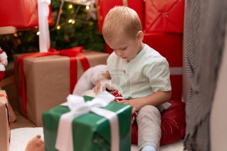 Téléchargez les photos : Adorable bambin assis sur le sol par des cadeaux de Noël à la maison - en image libre de droit