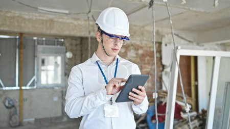 Photo for Young hispanic man architect standing with relaxed expression using touchpad at construction site - Royalty Free Image