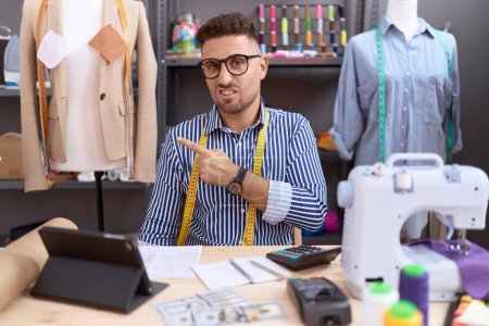 Photo for Hispanic man with beard dressmaker designer working at atelier pointing aside worried and nervous with forefinger, concerned and surprised expression - Royalty Free Image