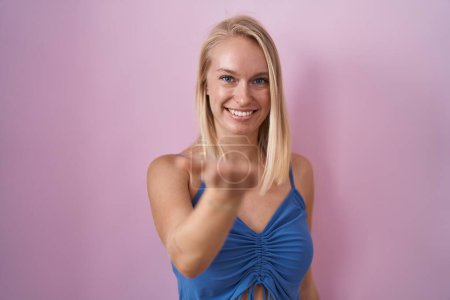 Téléchargez les photos : Jeune femme caucasienne debout sur fond rose souriant joyeuse offrant main de paume donnant assistance et acceptation. - en image libre de droit