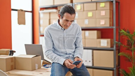Téléchargez les photos : Homme d'âge moyen e-commerce travailleur d'affaires en utilisant smartphone au bureau - en image libre de droit
