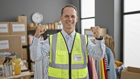 Photo for Smiling, confident middle-age man celebrates his own win as a charity volunteer at community center - Royalty Free Image