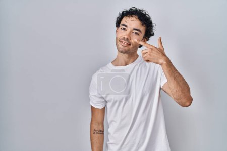 Téléchargez les photos : Homme hispanique debout sur fond isolé pointant avec le doigt de la main vers le visage et le nez, souriant gai. concept de beauté - en image libre de droit