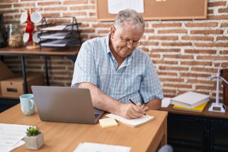 Photo for Middle age grey-haired man business worker using laptop writing on notebook at office - Royalty Free Image