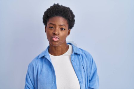 Photo for African american woman standing over blue background looking at the camera blowing a kiss on air being lovely and sexy. love expression. - Royalty Free Image