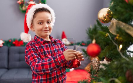 Foto de Adorable niño hispano sonriendo confiado decorando el árbol de Navidad en casa - Imagen libre de derechos