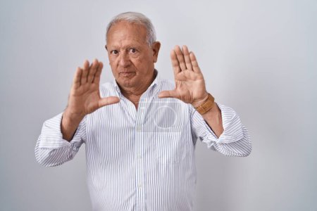 Photo for Senior man with grey hair standing over isolated background doing frame using hands palms and fingers, camera perspective - Royalty Free Image