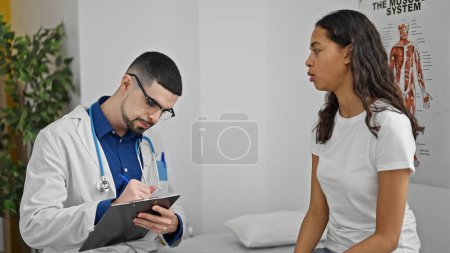 Foto de Trabajador sanitario serio se concentra en la redacción del informe médico del paciente en medio de la consulta clínica en la clínica - Imagen libre de derechos