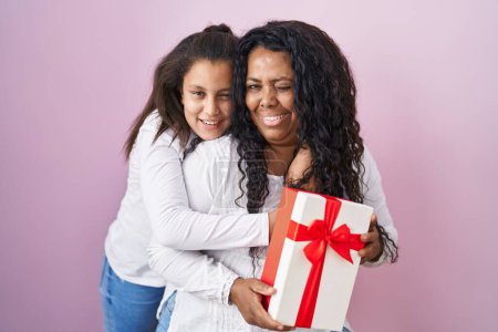 Téléchargez les photos : Mère et jeune fille tenant avec des cadeaux clin d'oeil en regardant la caméra avec une expression sexy, gai et heureux visage. - en image libre de droit
