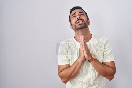 Photo for Hispanic man with beard standing over isolated background begging and praying with hands together with hope expression on face very emotional and worried. begging. - Royalty Free Image