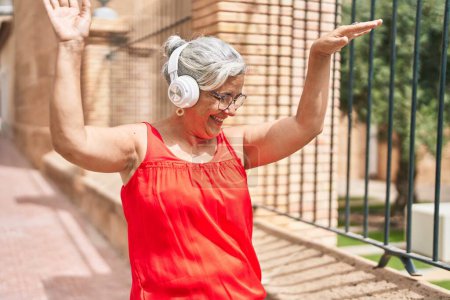 Téléchargez les photos : Femme aux cheveux gris du Moyen Âge écoutant de la musique et dansant dans la rue - en image libre de droit