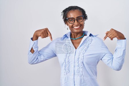 Photo for African woman with dreadlocks standing over white background wearing glasses looking confident with smile on face, pointing oneself with fingers proud and happy. - Royalty Free Image