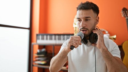 Téléchargez les photos : Jeune homme arabe musicien chantant chanson au studio de musique - en image libre de droit
