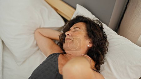 Téléchargez les photos : Moyen-âge hispanique femme couchée sur le lit souffrant de douleur cervicale dans la chambre - en image libre de droit