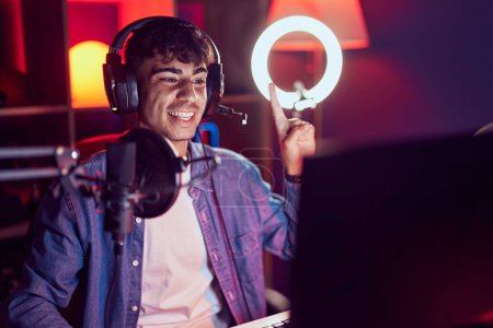 Téléchargez les photos : Jeune homme hispanique jouant à des jeux vidéo souriant avec une idée ou une question pointant du doigt avec un visage heureux, numéro un - en image libre de droit