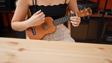 Foto de Joven hermosa mujer hispana músico jugando ukelele en estudio de música - Imagen libre de derechos