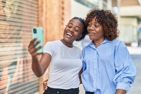 Téléchargez les photos : Les femmes afro-américaines mère et fille ayant appel vidéo à la rue - en image libre de droit