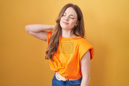 Photo for Caucasian woman standing over yellow background suffering of neck ache injury, touching neck with hand, muscular pain - Royalty Free Image