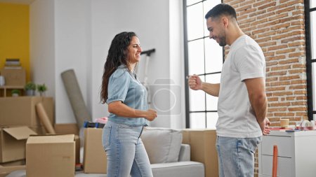 Foto de Hombre y mujer pareja jugando piedra tijeras papel juego sonriendo en nuevo hogar - Imagen libre de derechos