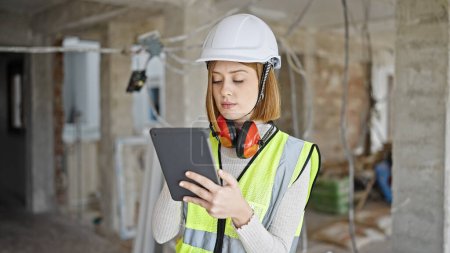 Photo for Young blonde woman architect using touchpad with serious expression at construction site - Royalty Free Image