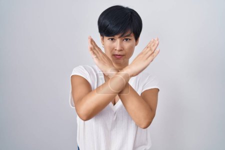 Photo for Young asian woman with short hair standing over isolated background rejection expression crossing arms doing negative sign, angry face - Royalty Free Image