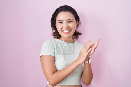 Téléchargez les photos : Jeune femme hispanique debout sur fond rose applaudissant heureux et joyeux, souriant mains fières ensemble - en image libre de droit