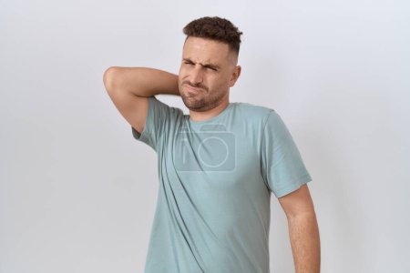 Foto de Hombre hispano con barba de pie sobre fondo blanco sufriendo de lesión de dolor de cuello, tocando el cuello con la mano, dolor muscular - Imagen libre de derechos