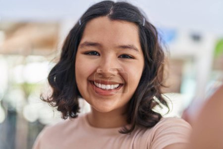 Téléchargez les photos : Jeune femme souriant confiant faire selfie par la caméra à la rue - en image libre de droit