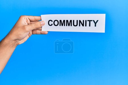 Photo for Hand of caucasian man holding paper with community word over isolated white background - Royalty Free Image