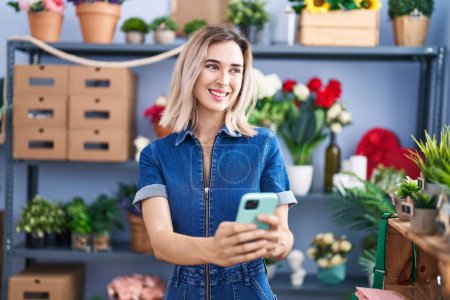 Téléchargez les photos : Young woman florist smiling confident using smartphone at florist - en image libre de droit