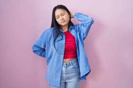 Téléchargez les photos : Young asian woman standing over pink background suffering of neck ache injury, touching neck with hand, muscular pain - en image libre de droit