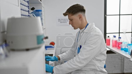 Photo for In the heart of the lab, young, handsome caucasian man-scientist expertly typing away on his computer, 100% focused on his on-going experiments and analysis. - Royalty Free Image