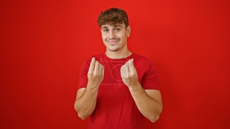 Photo for Cheery young hispanic man confidently flashing money sign, isolated over vibrant red background! - Royalty Free Image