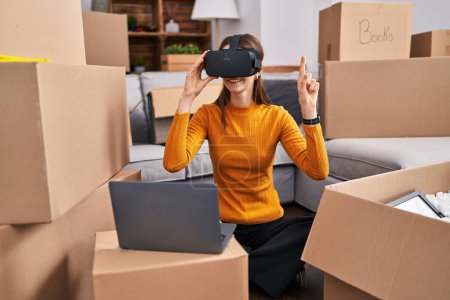 Foto de Joven mujer caucásica jugando videojuego usando gafas de realidad virtual en un nuevo hogar - Imagen libre de derechos