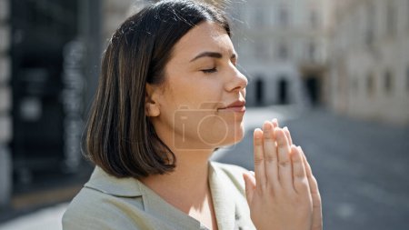 Photo for Young beautiful hispanic woman praying with closed eyes at cafeteria - Royalty Free Image