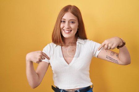 Photo for Young redhead woman standing over yellow background looking confident with smile on face, pointing oneself with fingers proud and happy. - Royalty Free Image
