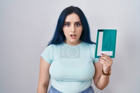 Photo for Young modern girl with blue hair holding l sign for new driver scared and amazed with open mouth for surprise, disbelief face - Royalty Free Image