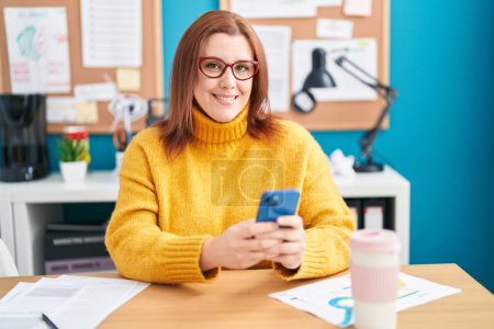Téléchargez les photos : Jeune belle femme de taille plus travailleur d'entreprise en utilisant un smartphone travaillant au bureau - en image libre de droit