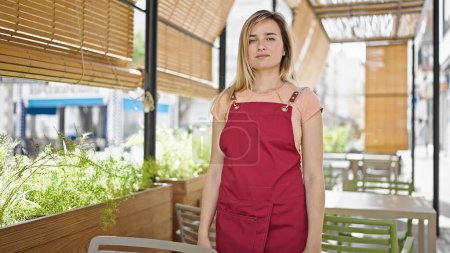 Photo for Young blonde woman waitress standing with relaxed expression at coffee shop terrace - Royalty Free Image